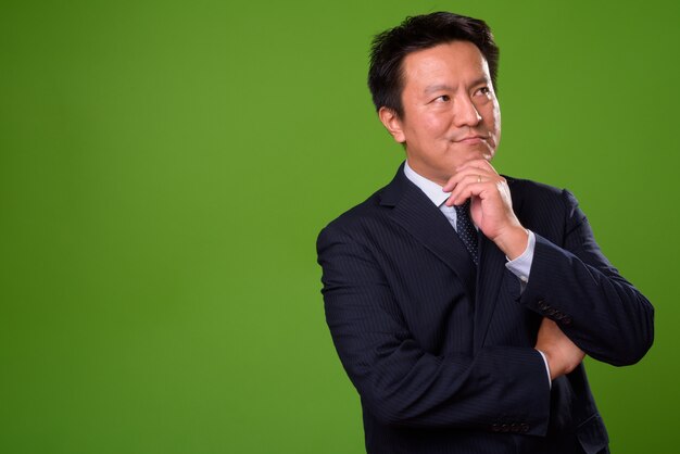 Mature Japanese businessman against green background