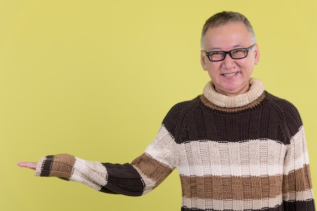  mature Japanese man with turtleneck sweater ready for winter against chroma key with green wall