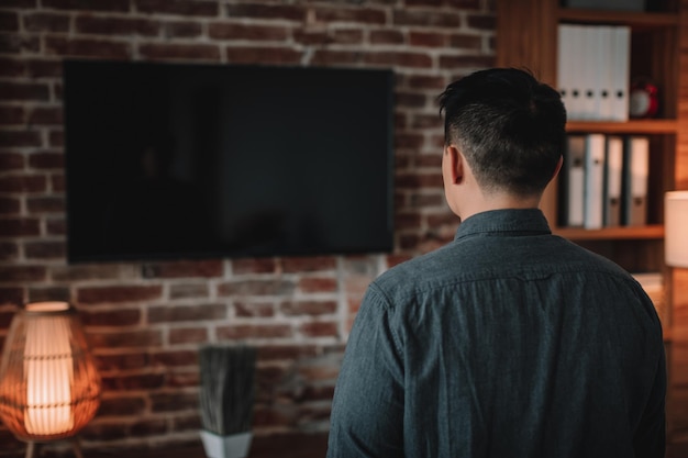 Mature korean man watching tv with empty screen enjoy show in home office interior back