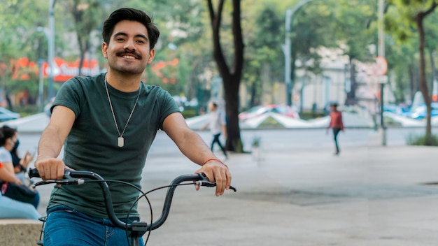 Uomo latino maturo con i baffi in sella a una bicicletta per le strade della città.