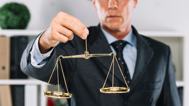 Photo mature lawyer holding golden scales of justice in hand