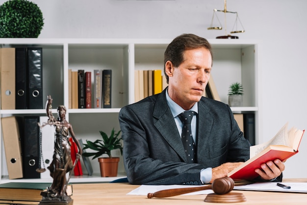 Foto avvocato maturo che legge il libro di legge nell'aula di tribunale