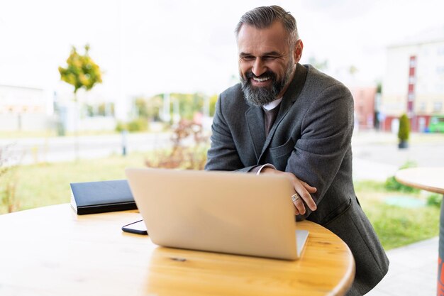 Mature male businessman working on laptop smiling outside