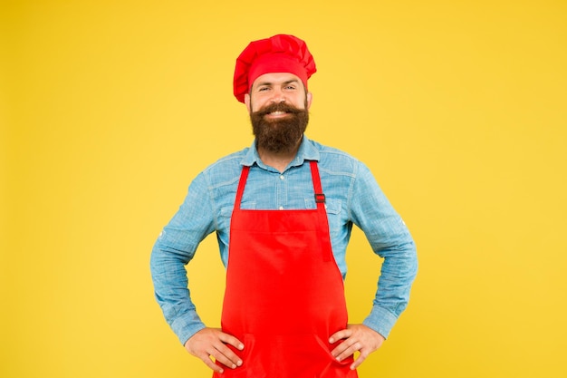Photo mature male chef on yellow backdrop man cooking on kitchen professional chef man excited and smiling excellent cook or baker special offer from chef chef in restaurant kitchen excellence