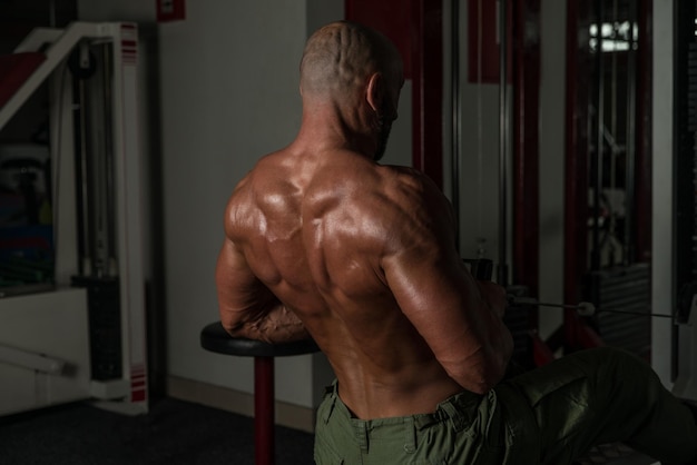 Photo mature male doing back exercises in the gym