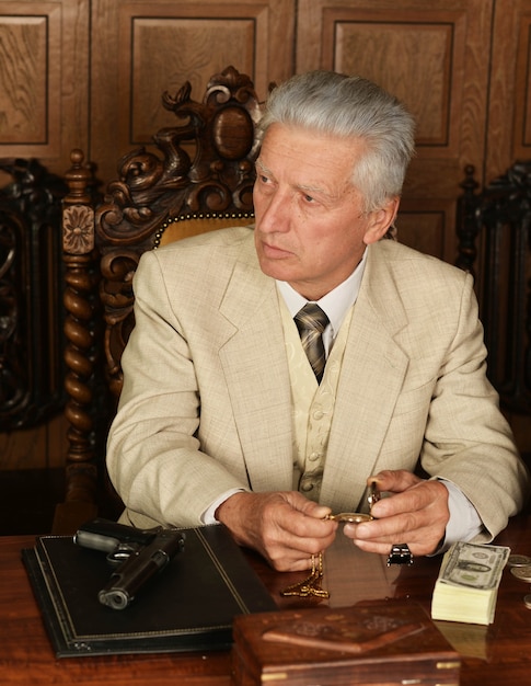 Photo mature male mafia boss on the table with gun