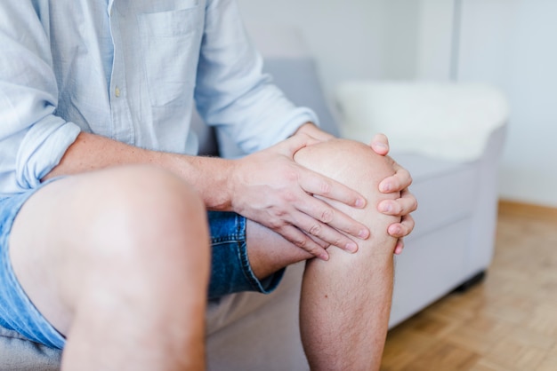 mature male patient holding knee in pain.