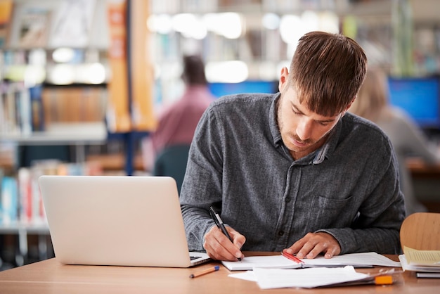 Mature Male Student Working On Laptop In College Library