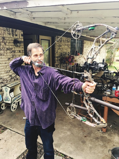 Photo mature man aiming through bow and arrow