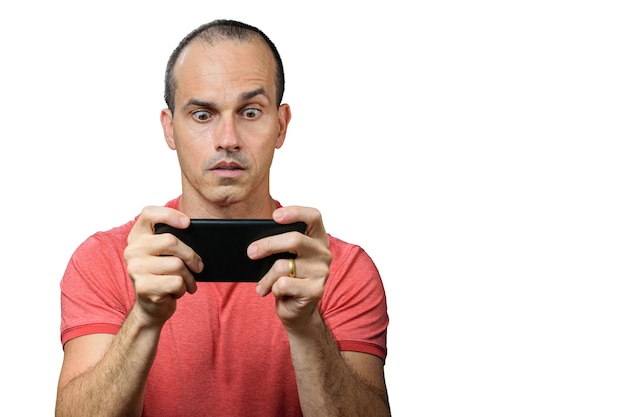 Mature man in casual clothing, wide-eyed and holding smartphone horizontally.