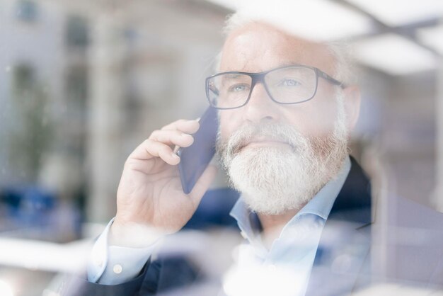 Mature man on cell phone behind windowpane