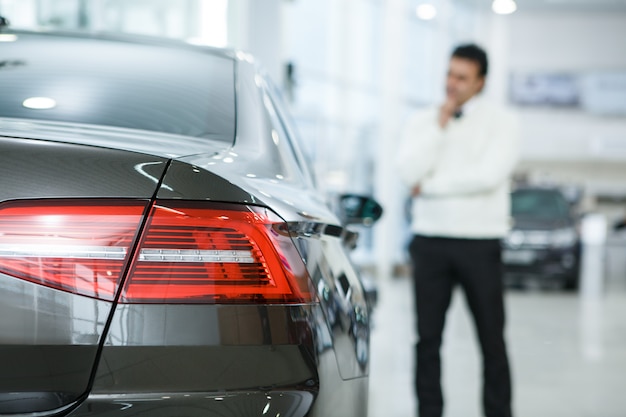 Mature man choosing a new car at the dealership salon