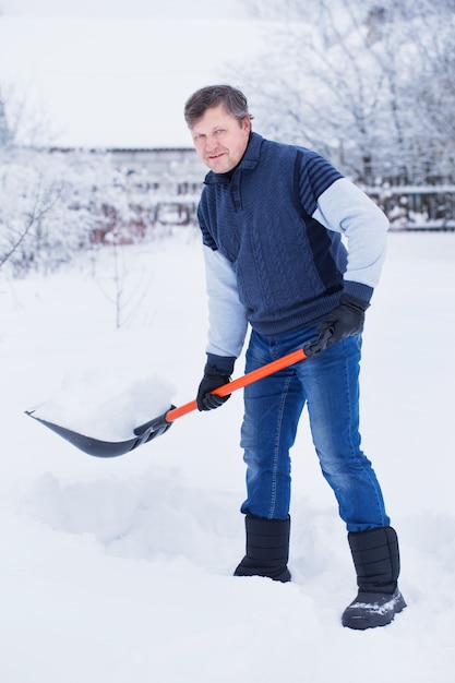 Mature man cleans snow shovel