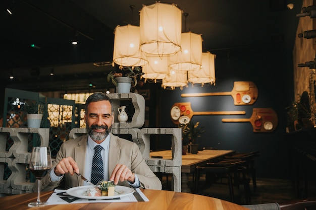 mature man drinking red wine during lunch