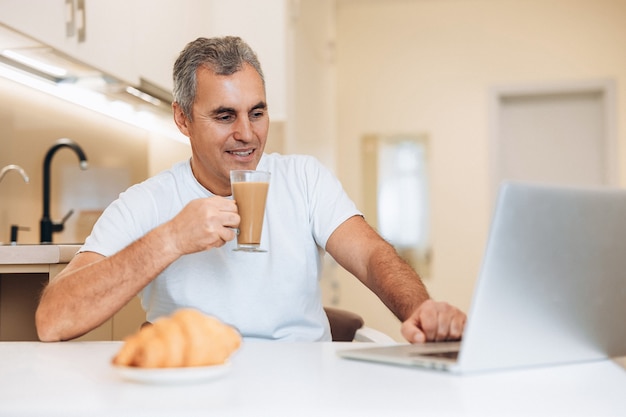 Mature man enjoing his cappuccino and yummy croissant