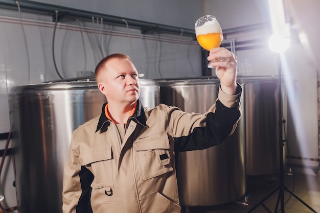 Фото Зрелый человек, изучения качества ремесленного пива на пивоваренном заводе. инспектор работает на алкогольной фабрике, проверяет пиво. мужчина в винокурне проверяет контроль качества разливного пива.
