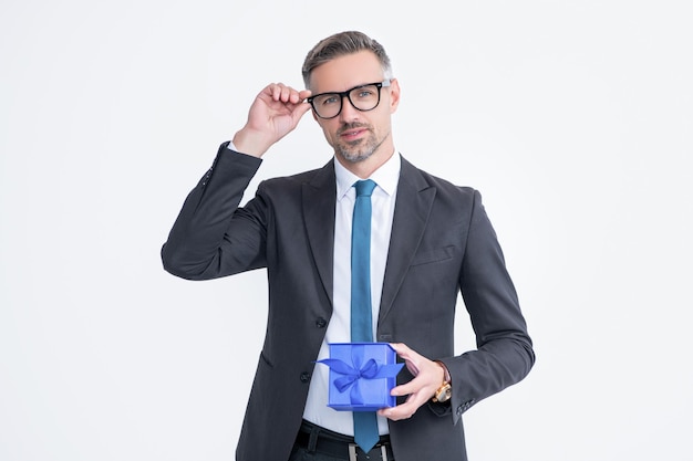 Mature man in eyeglasses and suit hold gift box isolated on white background