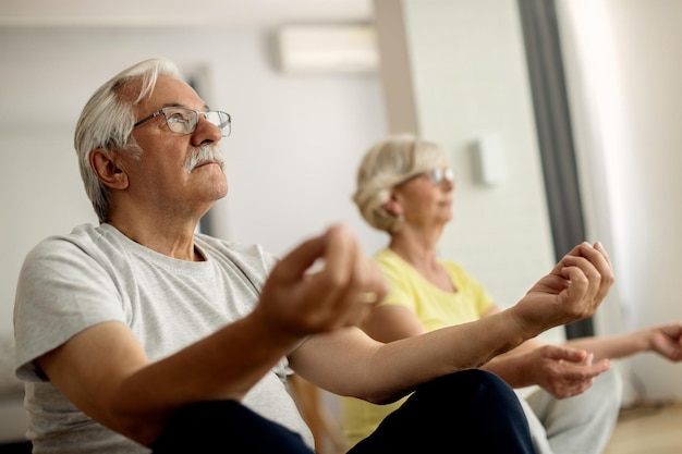 Mature man and his wife practicing Yoga at home