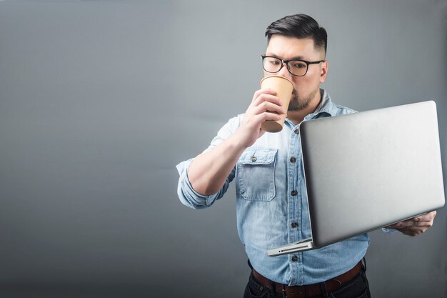 コンピューターとコーヒーを保持している中年の男性