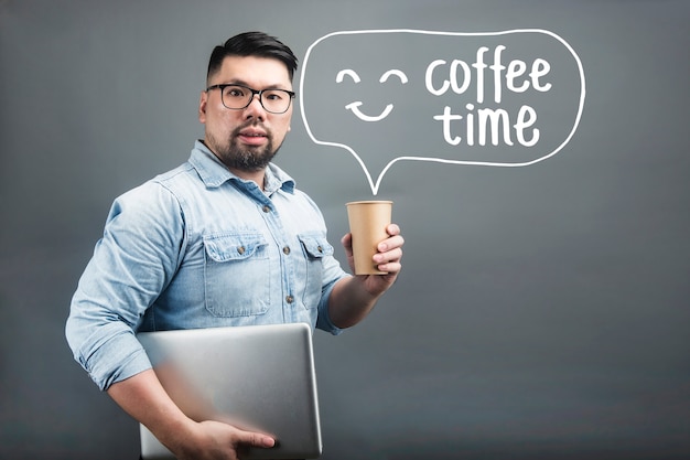 A mature man holding a computer and coffee