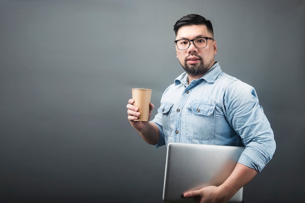 コンピューターとコーヒーを保持している中年の男性