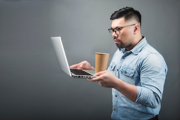 A mature man holding a computer and coffee