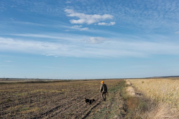 Mature man hunter with gun while walking on field