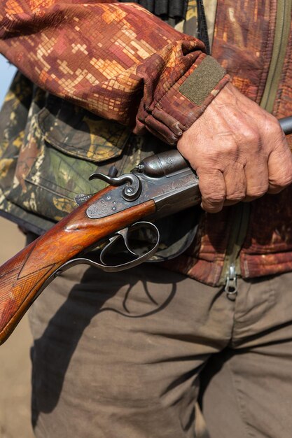 Foto uomo maturo cacciatore con una pistola mentre cammina sul campo