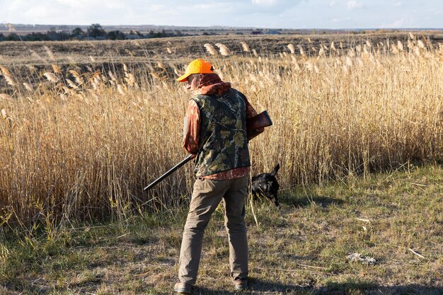 Photo mature man hunter with gun while walking on field