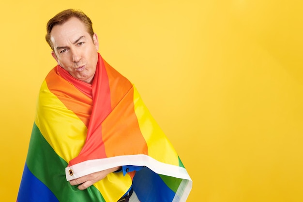 Mature man kissing while wrapping with a lgbt flag