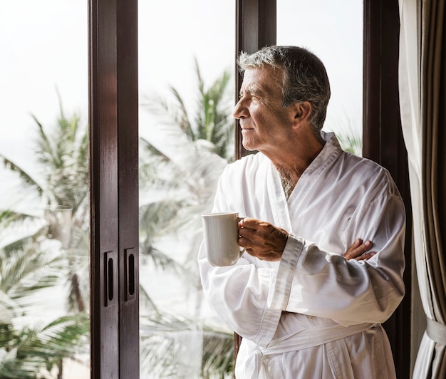 Uomo maturo guardando fuori dalla finestra dell'hotel