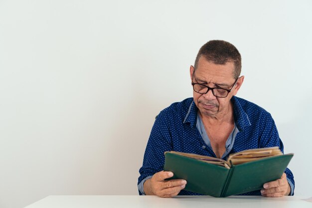 Mature man looking at a photo album sitting in her home