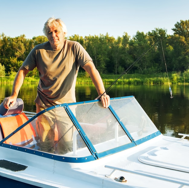 Зрелый мужчина на моторной лодке. Рыбная ловля.