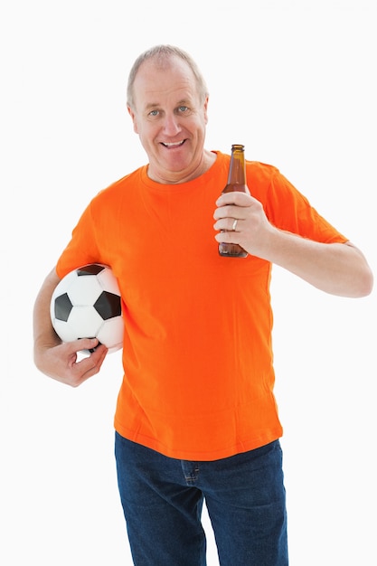Зрелый мужчина в оранжевой футболке с футболом и пивом