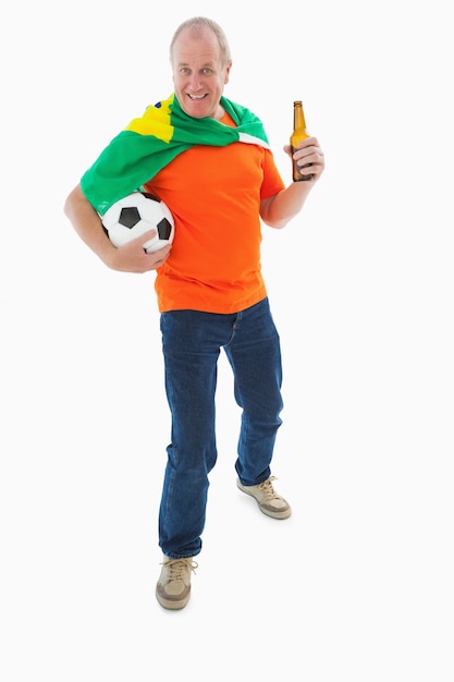 Mature man in orange tshirt holding football and beer