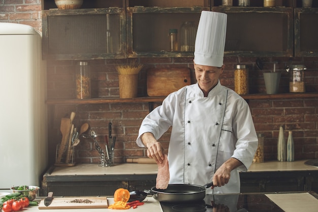 Mature man professional chef cooking meal indoors