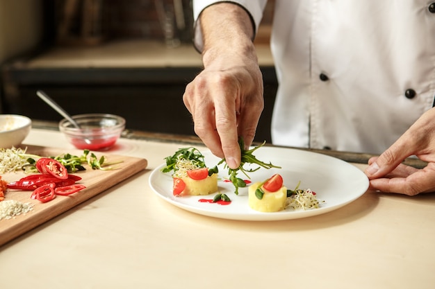 Chef professionista uomo maturo che cucina pasti al chiuso