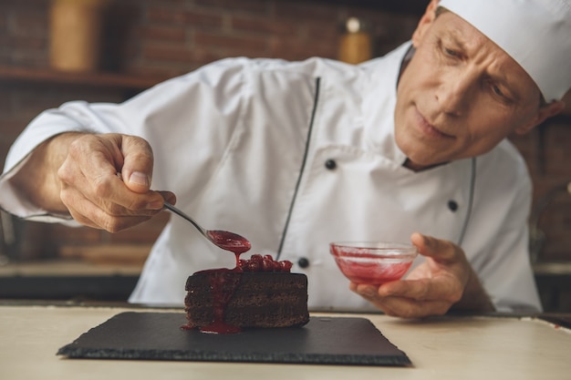 Foto chef professionista uomo maturo che cucina pasti al chiuso