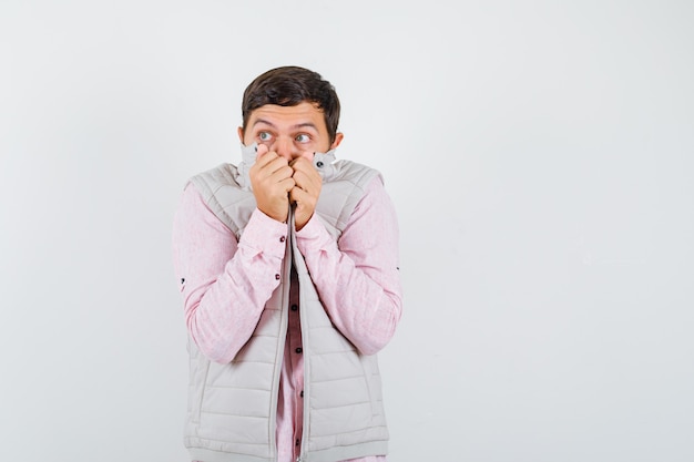 Photo mature man pulling his collar, looking away in shirt, sleeveless jacket and looking scared , front view.