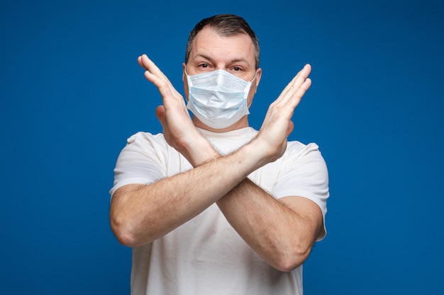 Mature man in safety mask showing stop gesture