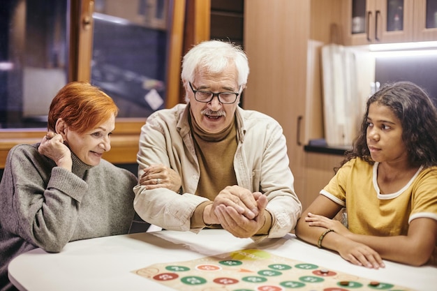 Mature man shaking dice in hands over board game