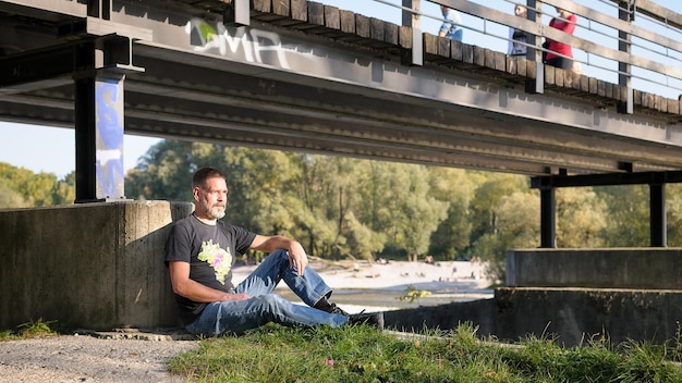 Photo mature man sitting under bridge