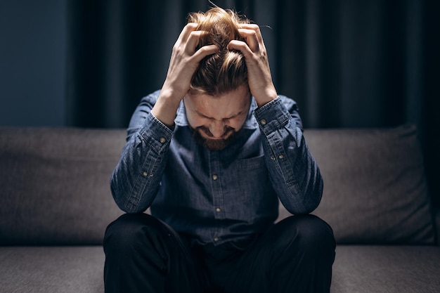 Mature man sitting at dark room and thinking about problems