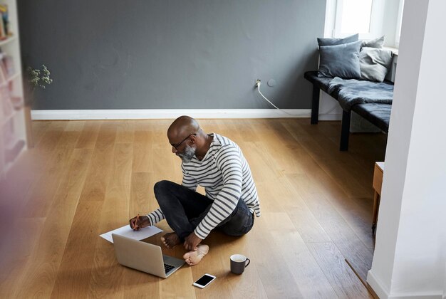 Mature man sitting on floor, working on laptop