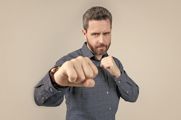 Mature man stand in fighting position with clenched fists in business casual style competition