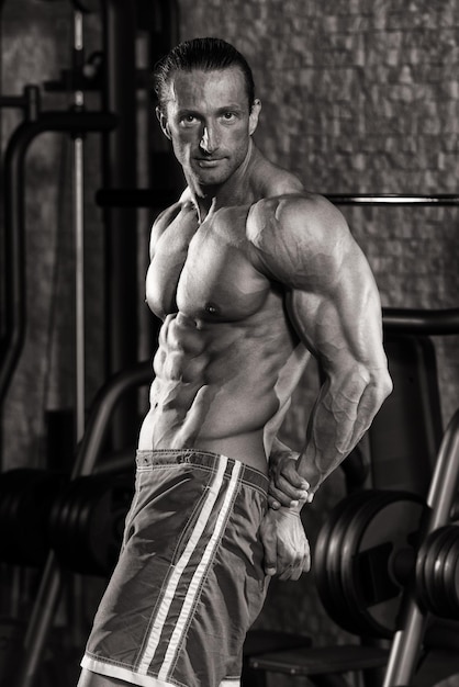 Mature Man Standing In Modern Fitness Center And Flexing Muscles