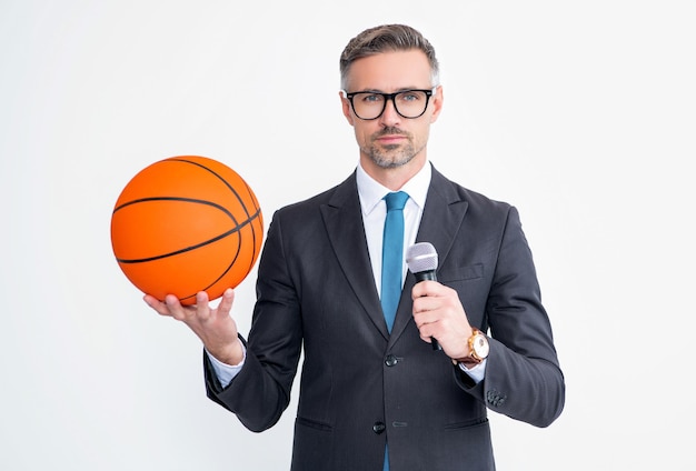 スーツの成熟した男は、白い背景で隔離のバスケットボールボールとマイクを保持します。