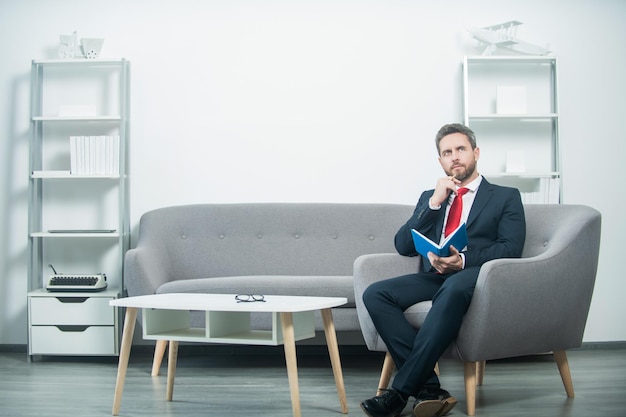 Mature man in suit sit in office with planner