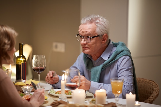 自宅のテーブルで夕食時に妻と話している成熟した男