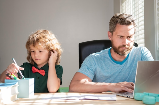 Mature man teacher or dad helping kid son with school homework on computer homeschooling